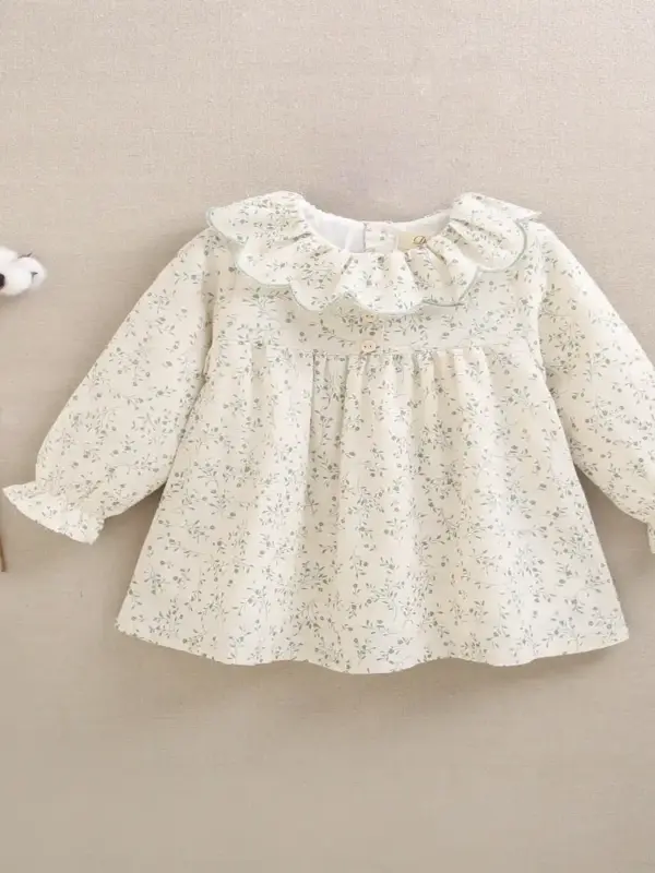 Vestido de bebé niña color crudo con estampado floral verde y volante en el cuello