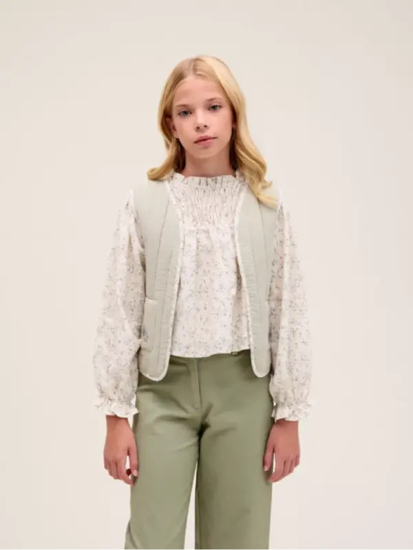 Chaleco de niña verde con detalle de flor en los bolsillos